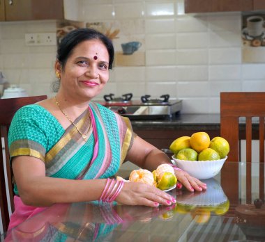 Kahvaltı masasında portakallı kadın, portakal yiyen Hintli kadın. Sağlıklı beslenme konsepti..