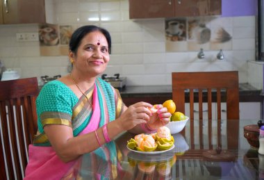 Kahvaltı masasında portakallı kadın, portakal yiyen Hintli kadın. Sağlıklı beslenme konsepti..