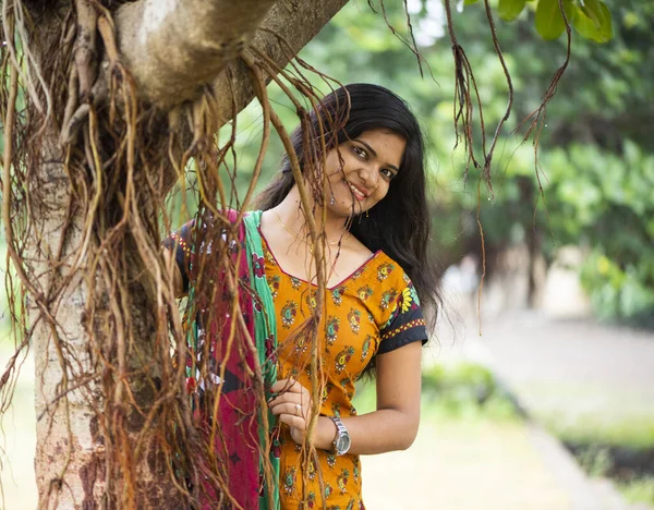 Happy Indian woman near banyan tree and holding roots.