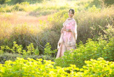 Doğada gün batımında geleneksel kıyafetler giyen güzel bir gelin portresi..