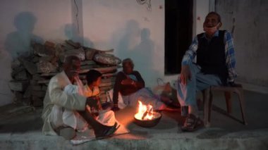 KHAJURAHO, MADHYA PRADESH, Hindistan, 05 Mart 2022: Kamp ateşi yakınında oturan ve dinlenen bir grup kırsal insan.