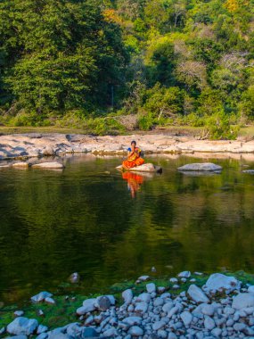 Yogada meditasyon yapan bir kadın dağ deresinde poz veriyor.