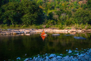 Yogada meditasyon yapan bir kadın dağ deresinde poz veriyor.