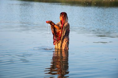 Geleneksel giyinmiş Hintli kadın Chhat Puja Festivali 'nde nehre dua ediyor..