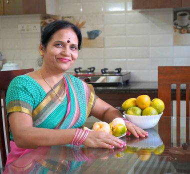 Kahvaltı masasında portakallı kadın, portakal yiyen Hintli kadın. Sağlıklı beslenme konsepti..