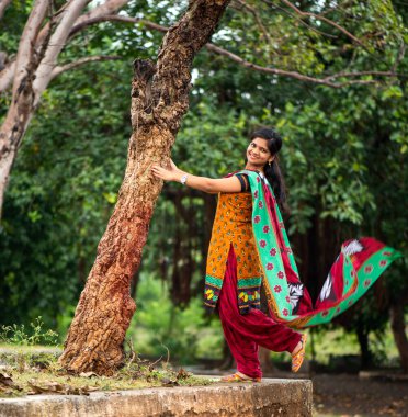 Ağaç gövdesinin yanında genç bir kız ve açık havanın tadını çıkarıyor.