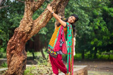 Ağaç gövdesinin yanında genç bir kız ve açık havanın tadını çıkarıyor.