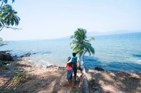 Denizin önünde oturan genç çiftin arka görüntüsü.