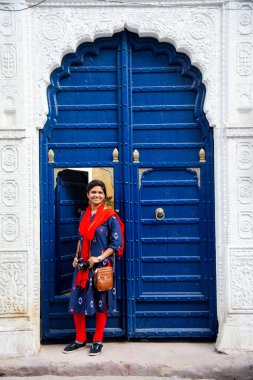 Genç bir kadının portresi renkli eski bir kapının önünde, Jodhpur, Rajasthan, Hindistan