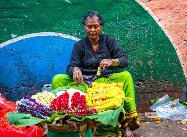 MUMBAI, INDIA, 28 ARALIK 2024: Dadar İstasyonu yakınlarındaki çiçek pazarında satmak için çiçek çelengi yapan kadın.