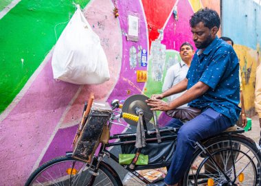 MUMBAI, INDIA, 28 Aralık 2024: Demirci, Dadar İstasyonu yakınlarındaki çiçek pazarında bir bıçağı bilemek için disk makinesi kullanıyor.
