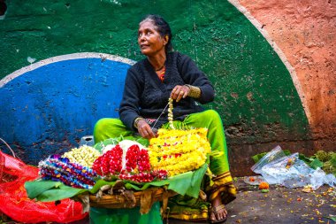 MUMBAI, INDIA, 28 ARALIK 2024: Dadar İstasyonu yakınlarındaki çiçek pazarında satmak için çiçek çelengi yapan kadın.