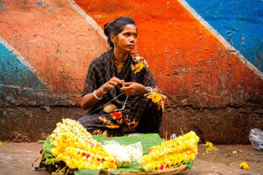 MUMBAI, INDIA, 28 ARALIK 2024: Dadar İstasyonu yakınlarındaki çiçek pazarında satmak için çiçek çelengi yapan kadın.