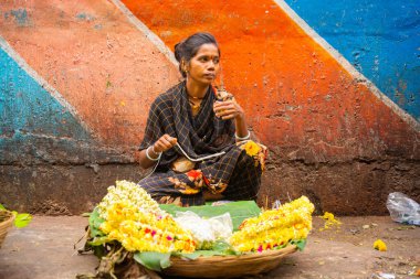 MUMBAI, INDIA, 28 ARALIK 2024: Dadar İstasyonu yakınlarındaki çiçek pazarında satmak için çiçek çelengi yapan kadın.