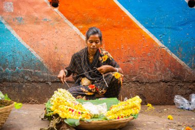 MUMBAI, INDIA, 28 ARALIK 2024: Dadar İstasyonu yakınlarındaki çiçek pazarında satmak için çiçek çelengi yapan kadın.