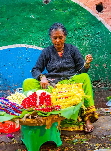 MUMBAI, INDIA, 28 ARALIK 2024: Dadar İstasyonu yakınlarındaki çiçek pazarında satmak için çiçek çelengi yapan kadın.