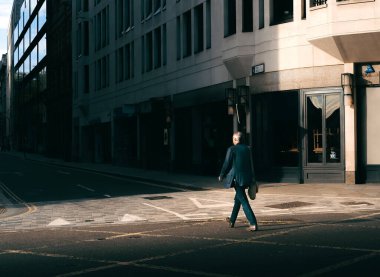 Caddede Yürüyen Adam 'ın Altın Güneş Işığının Kuyusu' nda ve Londra, İngiltere 'de Karanlık Gölgeler' de fotoğrafı