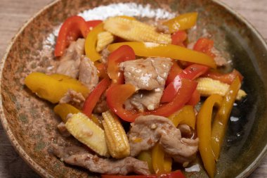 Kahverengi bir tabakta tatlı biberli kızarmış domuz eti.