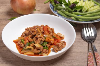 Pork stir fried in chili paste with tomatoes and onions in a white dish