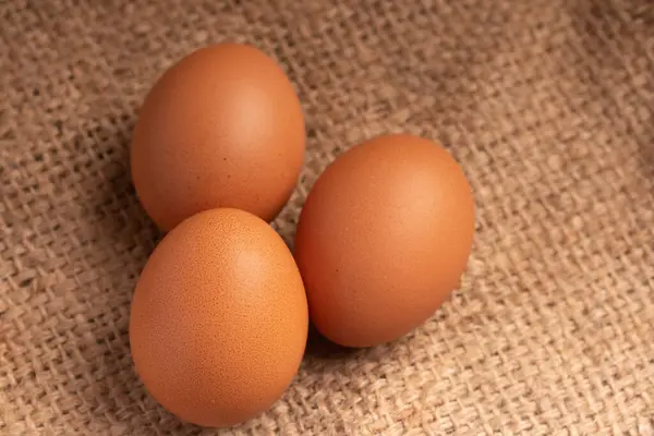 茶色の背景に3つの新鮮な鶏の卵 — ストック写真