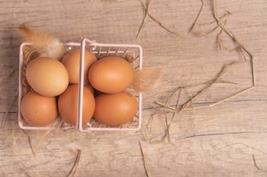 Tahta bir arka planda sepetteki taze yumurtalar. Boşluğu kopyala..