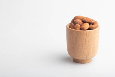 Beyaz arka planda tahtadan bir fincanda badem.