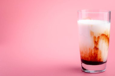 Fresh brown sugar milk in a clear glass on pink background