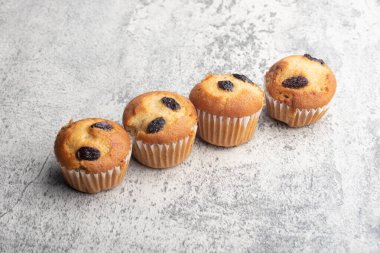 Banana cupcakes sprinkled with raisins. Copy space on gray background.