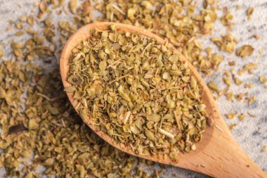oregano in wooden spoon on gray background