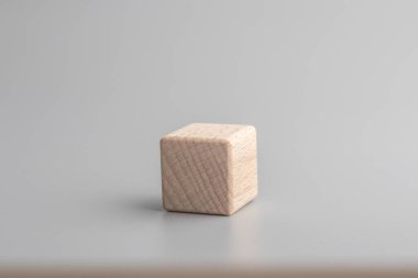 Simple empty wooden dice, one blank cubes made of wood with one central element, gray background. Copy space, logo space in the middle.
