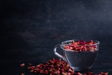 Rose tea in transparent glass on black background