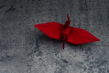 Red paper crane on gray background. Symbol of hope.