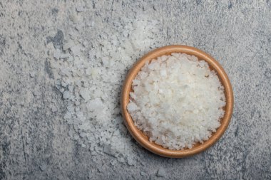 Sea salt in wooden cup on gray background