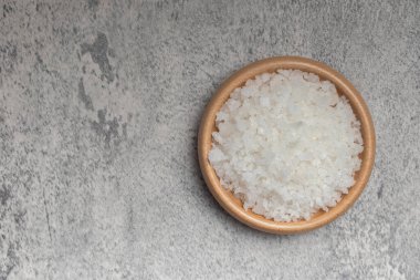 Sea salt in wooden cup on gray background