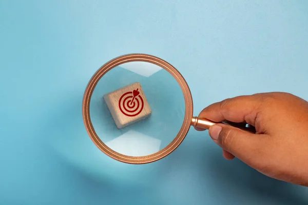 Magnifying glass with wooden block, target symbol.Work targeting concept.