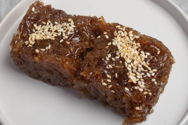 Kahverengi şekerli kızarmış pilav, beyaz susamlı tatlı.