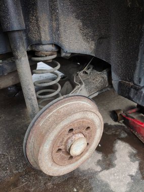 Arka paslı araba diski silinmiş tekerlek, fren pedi ve araba yayı yakın plan.