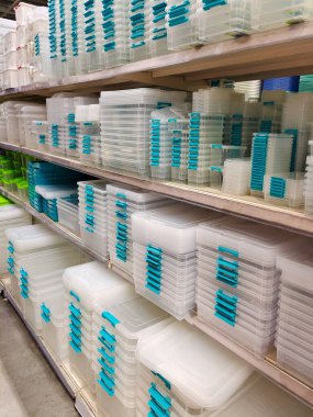 Farklı şekil ve renklerde plastik kaplar bir mağazanın perspektifinde raflarda satılıyor.