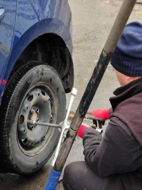 Islak asfalt üzerinde araba servis istasyonunda araba krikosunda tekerlek değiştirmek
