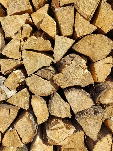 View of chopped firewood, logs piled together for storage. Close up of wooden background and texture. Collection of dry village wood as a source of energy
