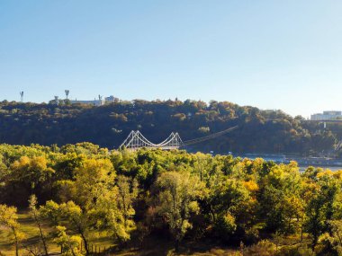 Büyük bir parkın ötesindeki ufukta nehrin üzerinde kablolu bir köprü. İHA 'yla yükseklerden ateş etmek