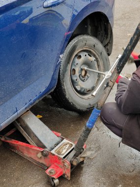 Tamirci arabanın tekerleğinin yanına oturur ve vidaları yerine koymak için özel bir anahtarla söker. Üst görünüm