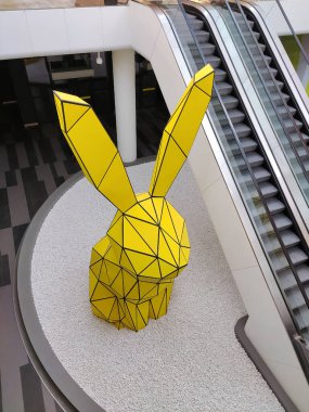 A decorative yellow rabbit statue near an escalator in a public place. View from above