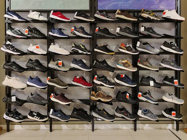 Rows of different sneakers of different brands are displayed on the shelves of a shoe store. Editorial photo on trade topics