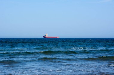 A view of the panorama of the blue sea and sky. Sea idyll. A lone freighter in the distance. Small sea waves