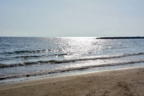 Glistening sea waves roll onto the shoreline of a sandy beach