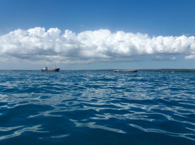 İki gemi denizde yelken açıyor. Deniz ve gökyüzü çeşitli türkuaz ve mavi tonlarda. Beyaz bulutlu parlak doğal arkaplan
