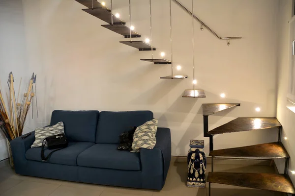 青銅製のアパートで装飾的な階段 その上にはランプの光がある 階段の下に枕があるソファ 現代的なアパートのコンセプト — ストック写真