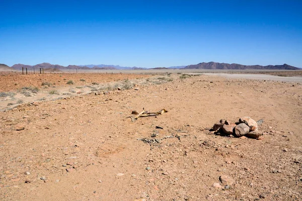 Waterless desert valley to the horizon against the background of the blue sky. World climate change and global warming. A pile of stones in the foreground