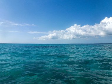 Deniz ve gökyüzü çeşitli türkuaz ve mavi tonlarda. Beyaz bulutlu parlak doğal arkaplan